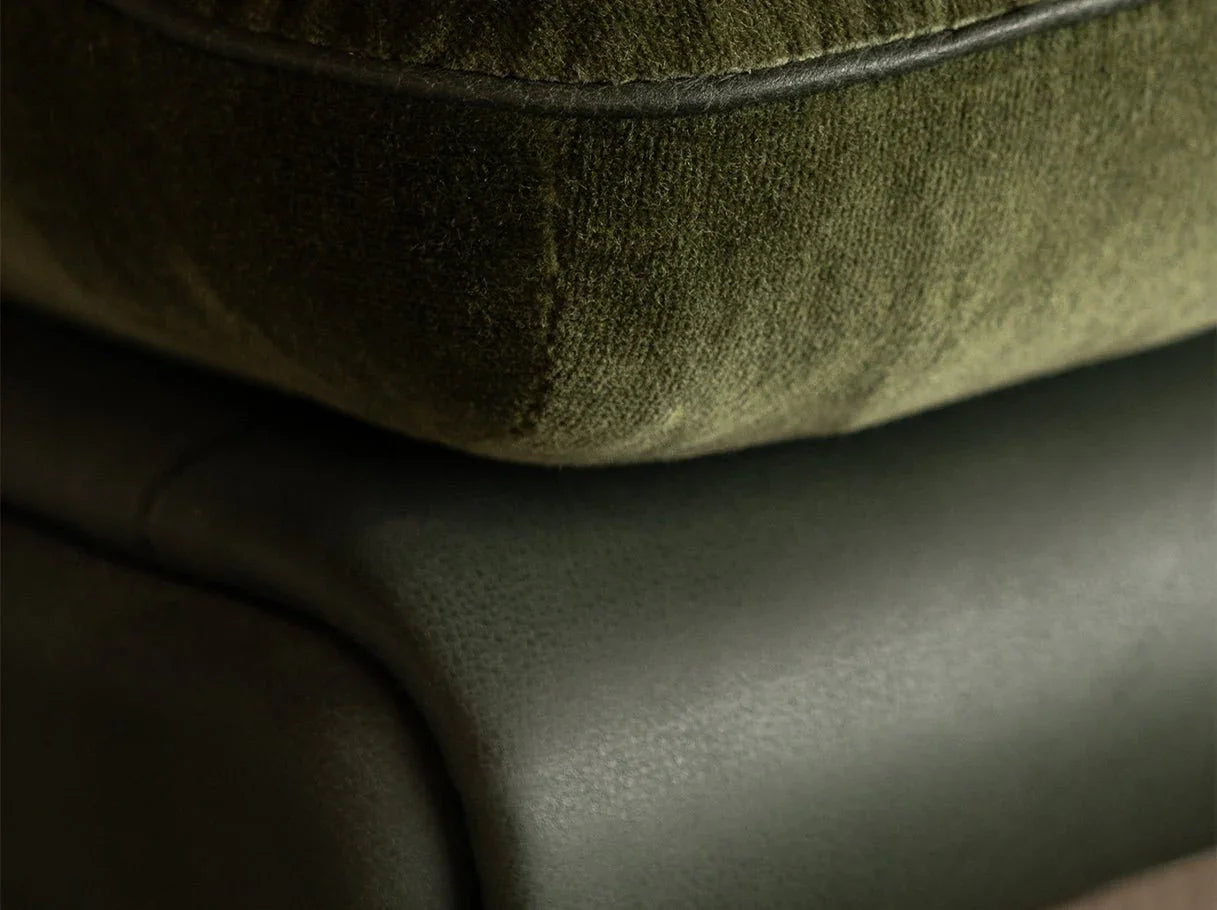 Close-up of comfy armchair upholstery in aniline leather and velvet blend, highlighting refined stitching
