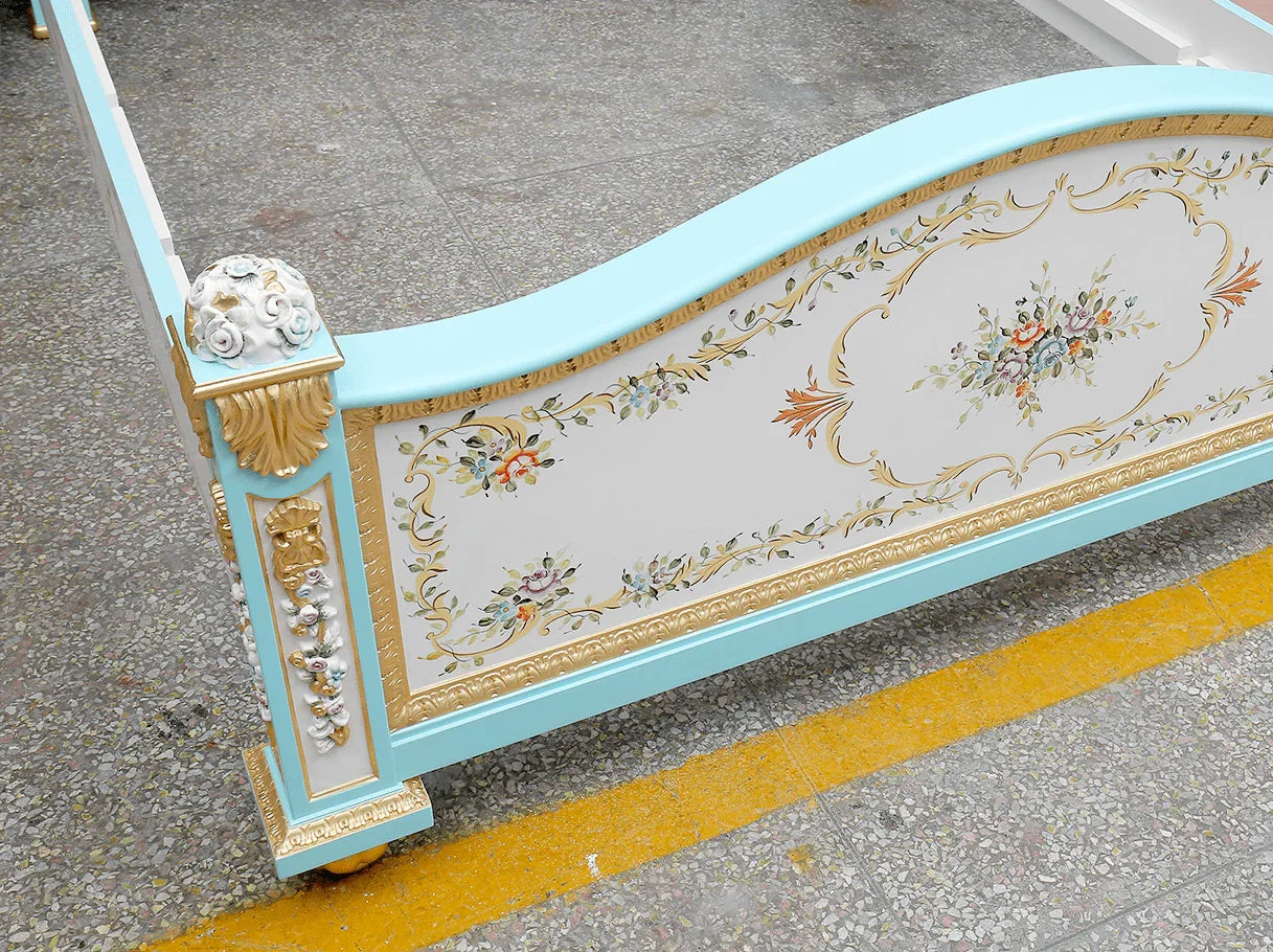 Detail view of B-016 French bed frame with gold leaf carvings, arched profile, and artisanal hand-painted floral decorations.