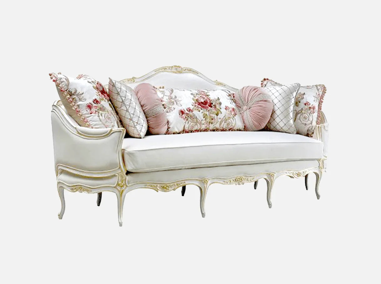 Side view of a French sofa in white with floral cushions, showcasing hand-carved beech wood frame and elegant gold leaf detailing.