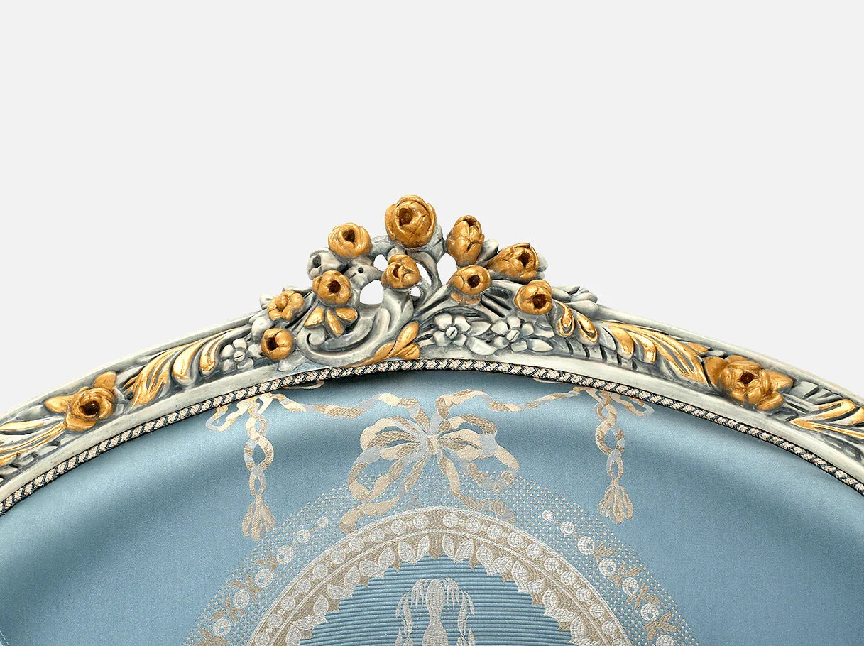 Ornate crest detail of French armchair A-1188 with gold leaf floral carvings on beech wood frame.
