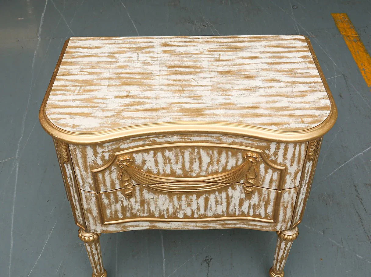 Golden finish nightstand with sculptural carved motifs and smooth top