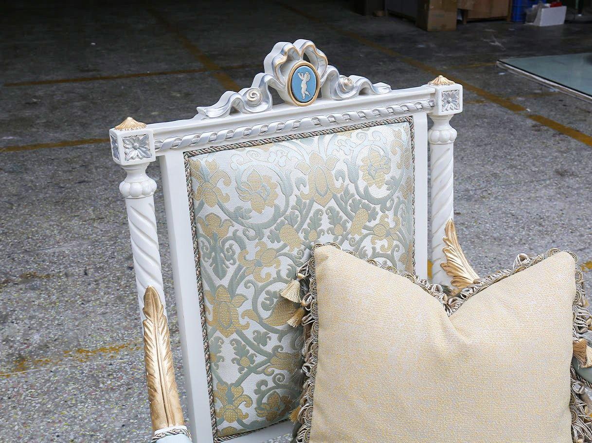 Close-up of French armchair A-0020 backrest detail with silvery damask jacquard, carved crest, and soft decorative pillow.