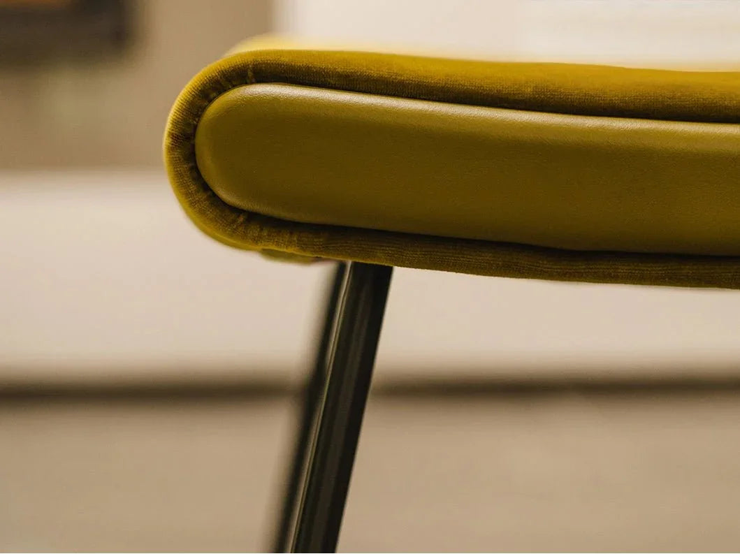 Close-up of comfy armchair upholstery in aniline leather and velvet blend, highlighting refined stitching